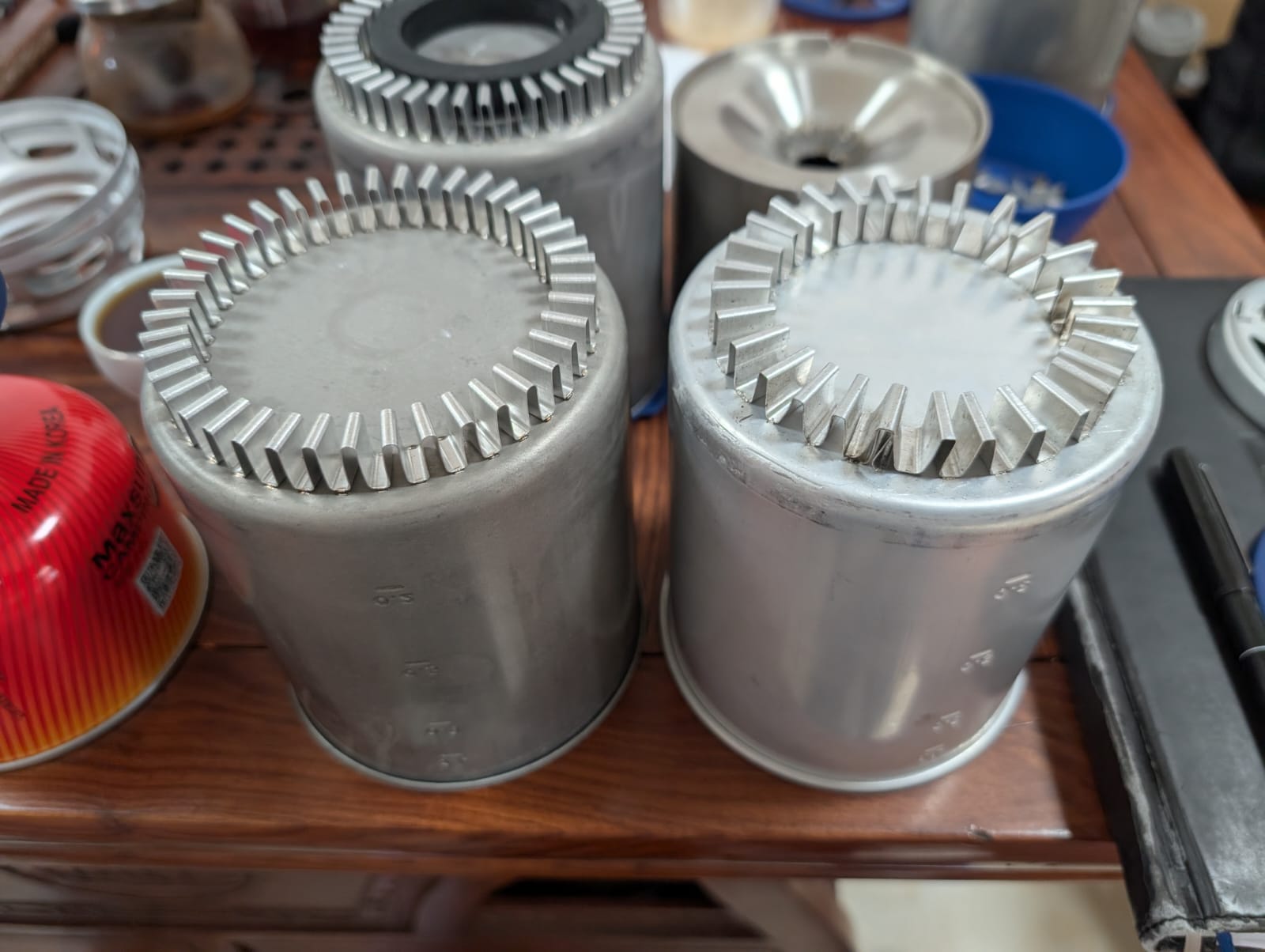 Several welded burner cups lined up on a workbench
