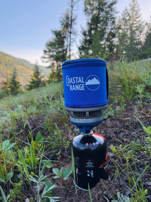 Close-up of the blue-sleeved Backpacker stove in a mountain meadow at sunrise