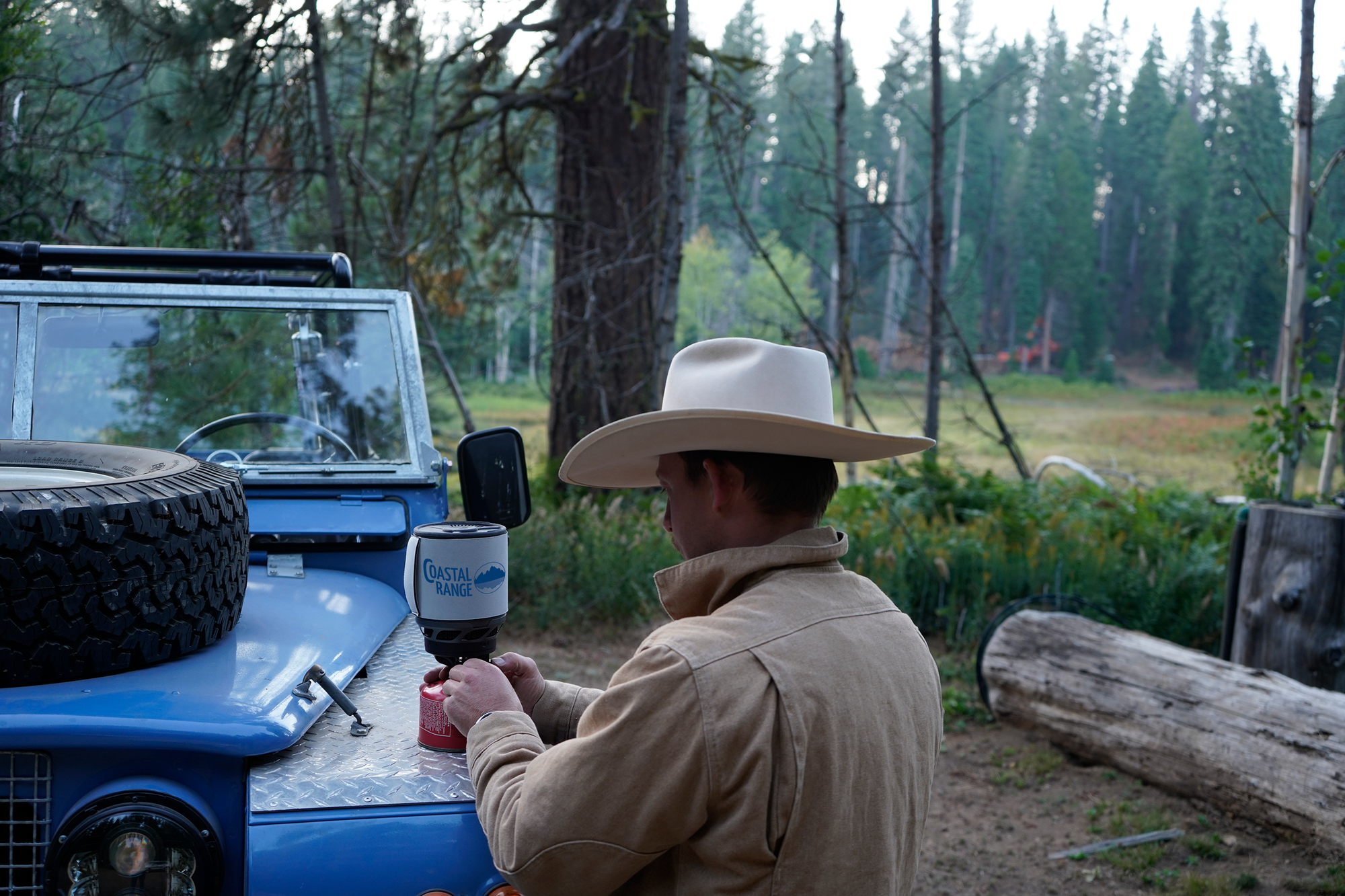 A camper brewing up with the Backpacker on a Land Rover in the pines