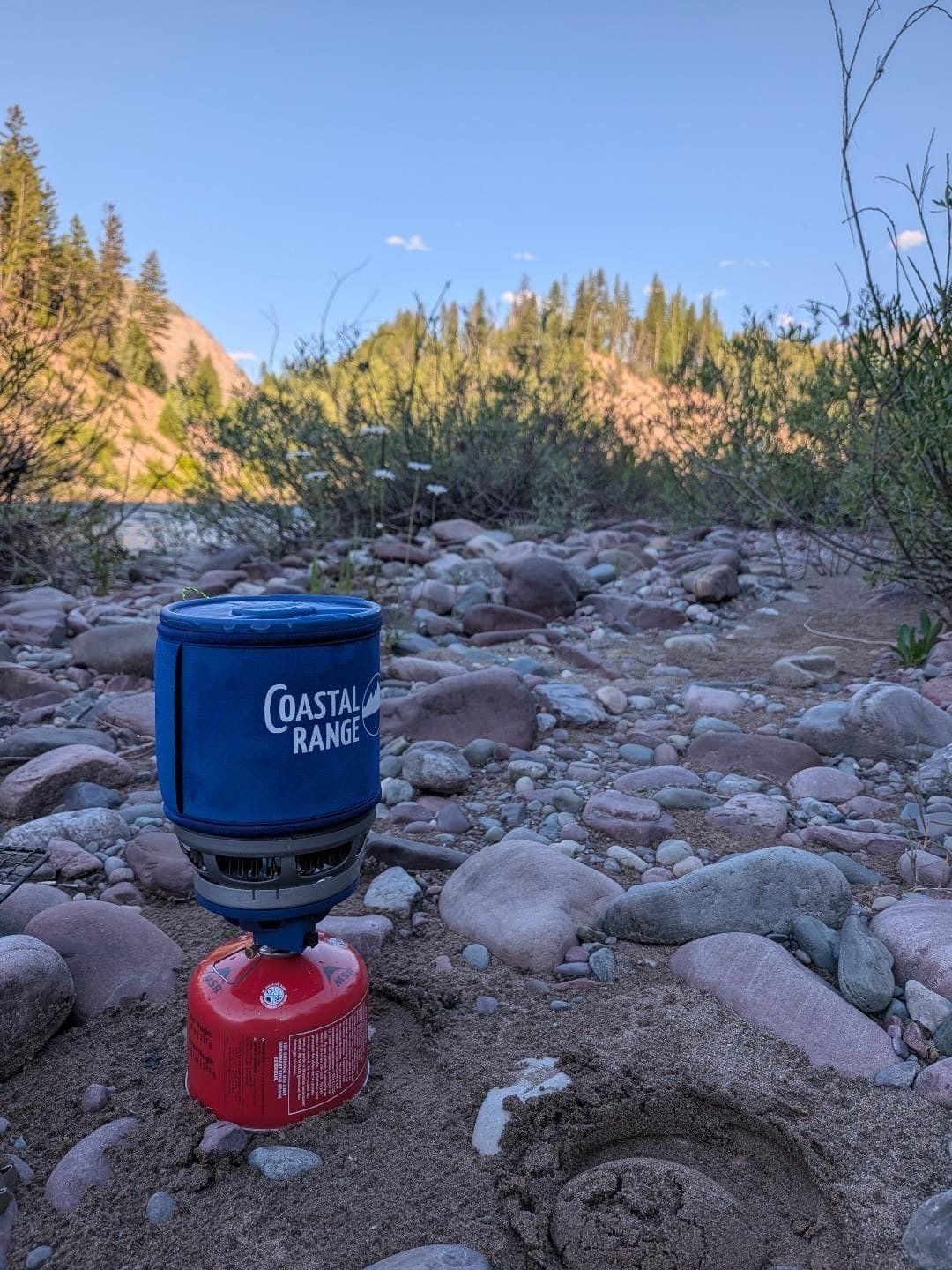The Backpacker stove boiling water on a riverbank during a Bob Marshall Wilderness packraft trip